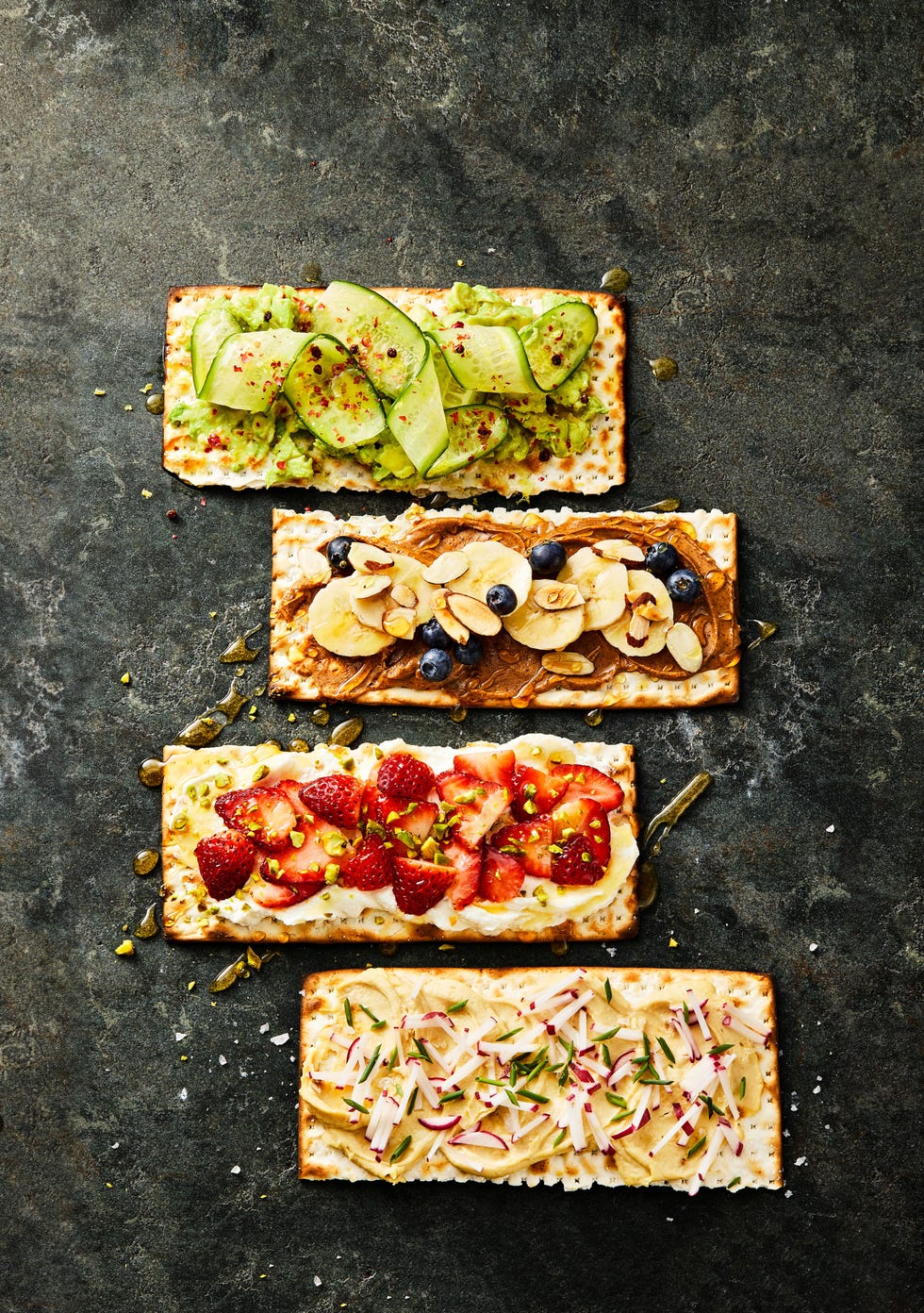matzo toasts with a variety of toppings that consist of cucumbers, bananas, strawberries, and apples