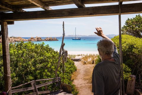 Vanaf zijn veranda wuift Morandi naar een passerende boot Hoewel het strand in de jaren negentig van de vorige eeuw voor toeristen werd gesloten hebben bezoekers beperkt toegang tot delen van het eilandje