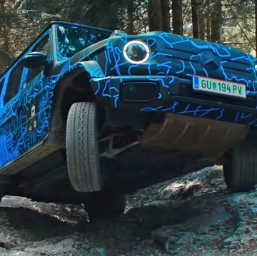a blue car with a dent in the front driving on a dirt road