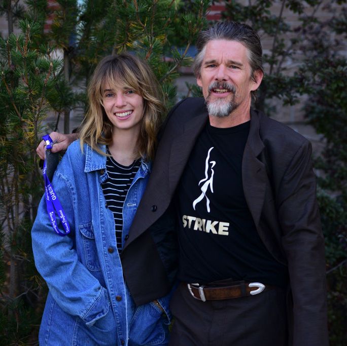 maya hawke and ethan hawke pose for photo together while standing in front of some greenery
