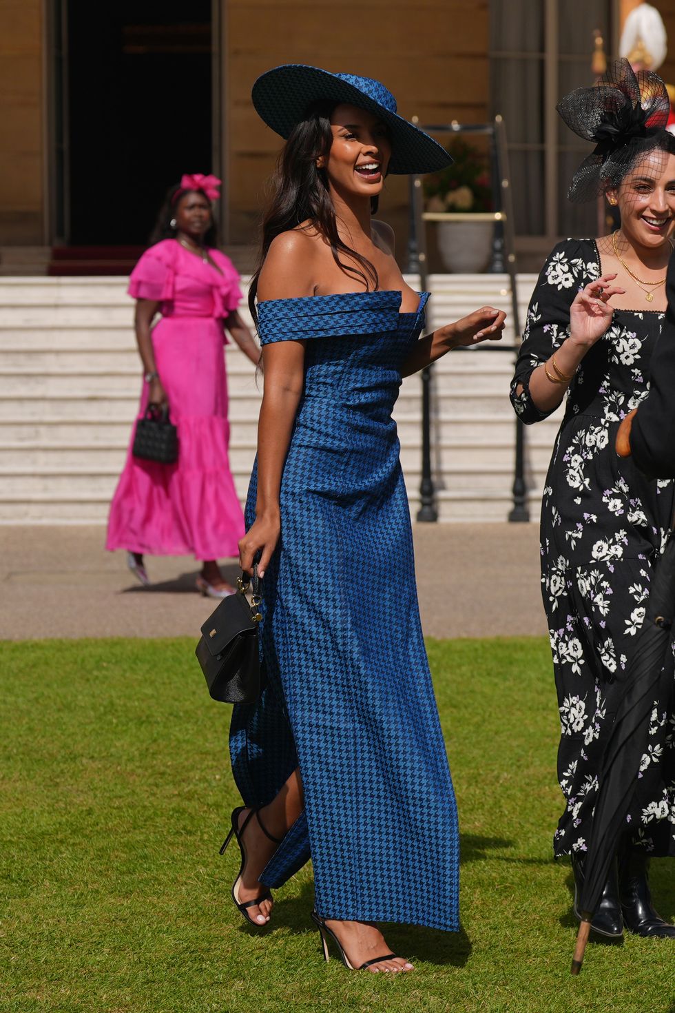 maya jama wears a blue hat and dress at buckingham palace