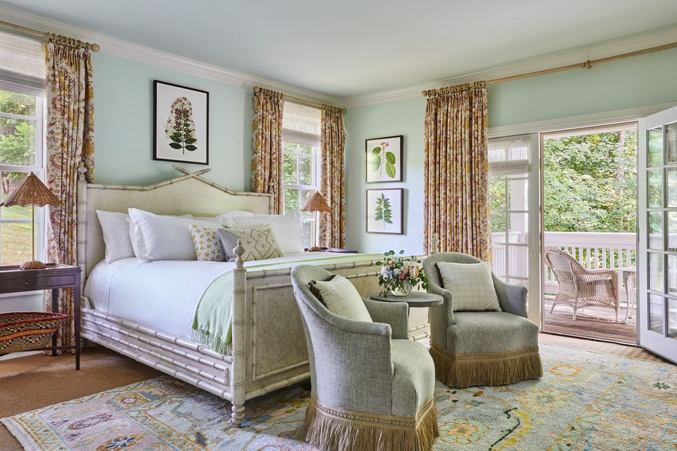 light blue walls with a bed that has an off white headboard, white sheets, and a light green blanket on it