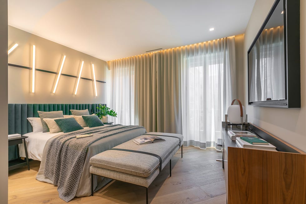 dormitorio con cabecero de terciopelo verde y apliques