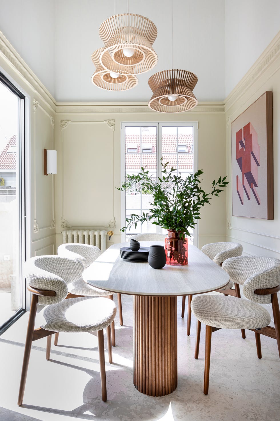 mesa de comedor ovalada con patas de palillería y sillas con tapizado beige
