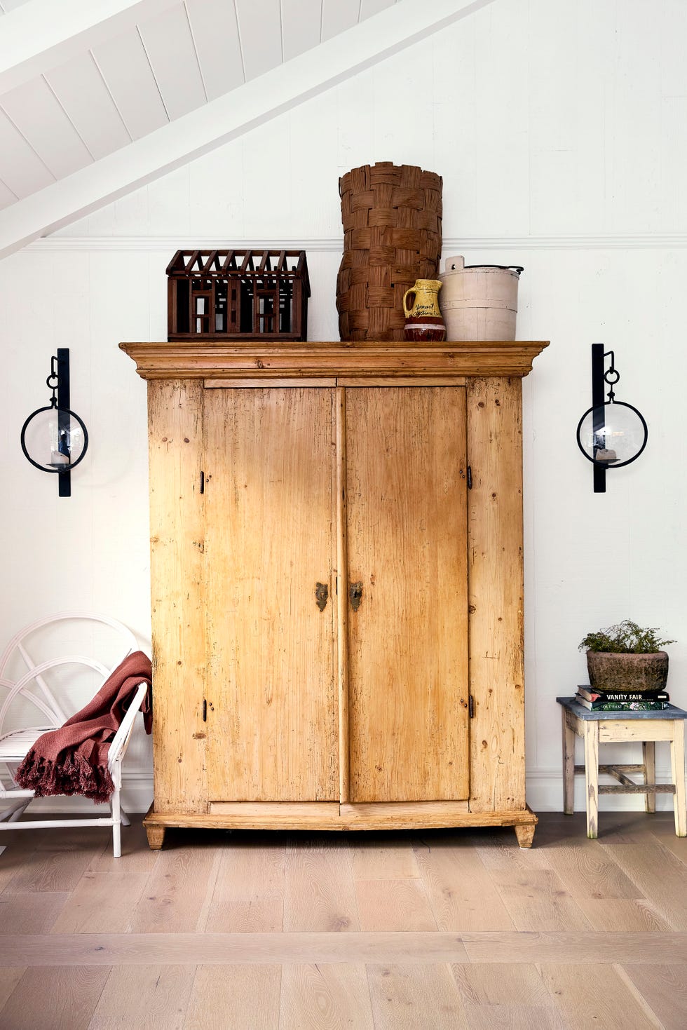 large wood wardrobe against a white wall with a light fixture on either side of it