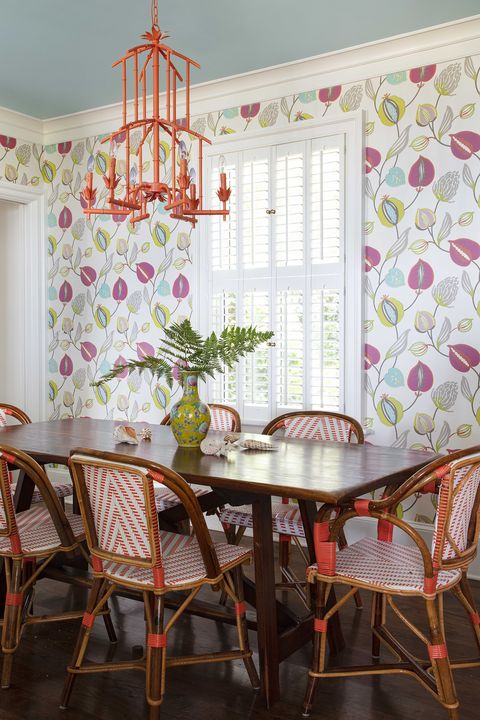 dining room with floral wallpaper, wooden table and white and orange rattan dining chairs