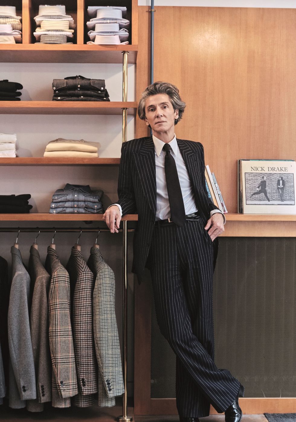 a person in a suit standing in front of a closet full of clothes