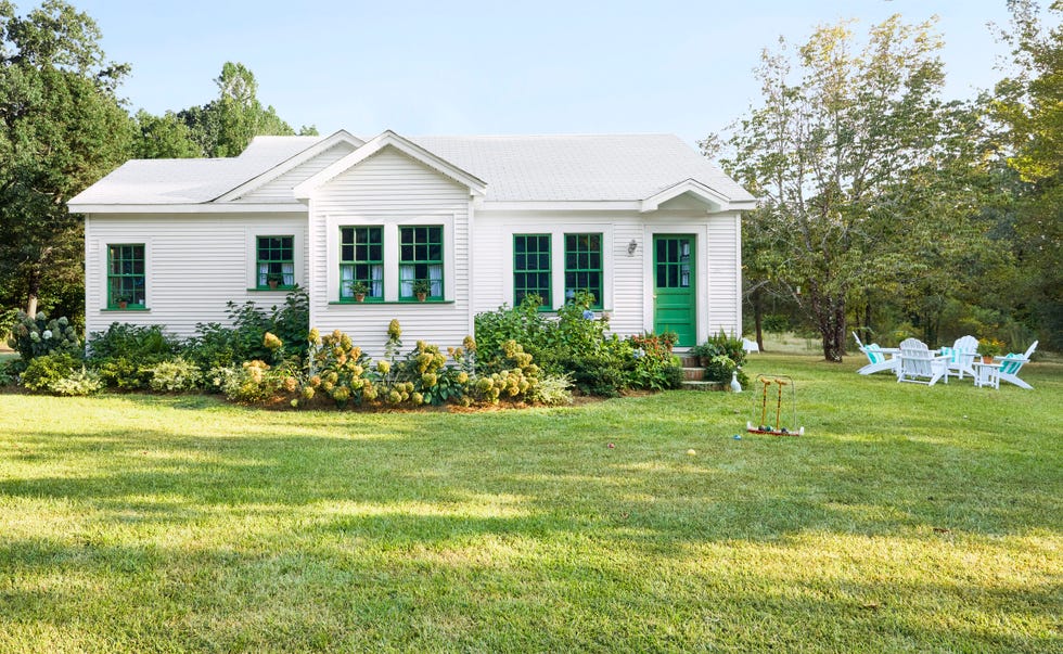 a single story white house with a green front door and window trim