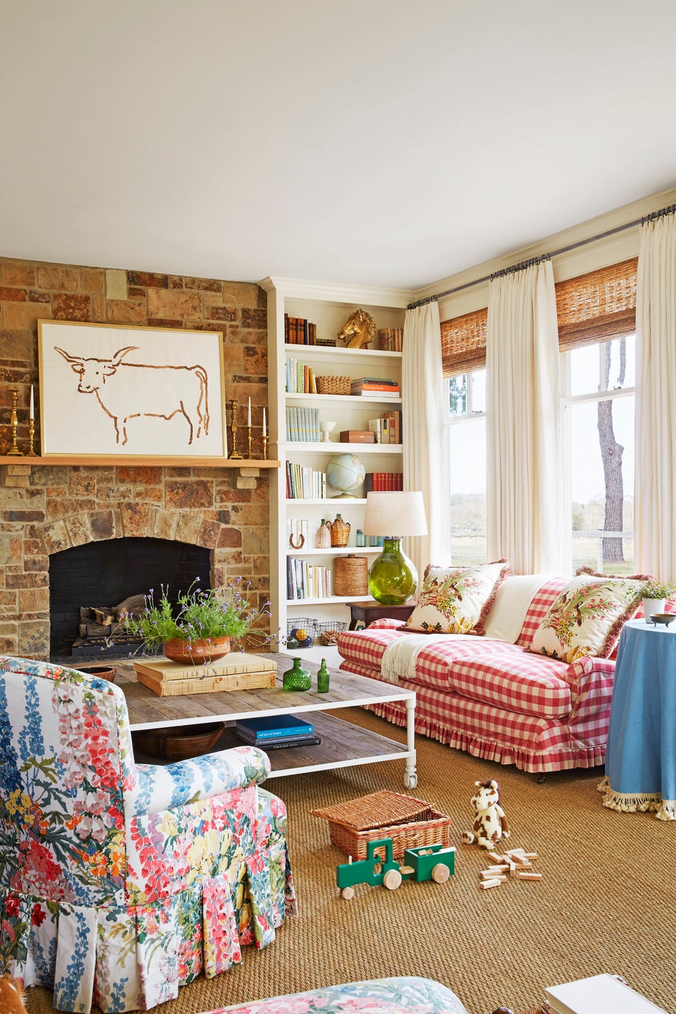 a living room with a fireplace, floral chair, red checked sofa