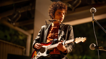 musician performing with an electric guitar and harmonica