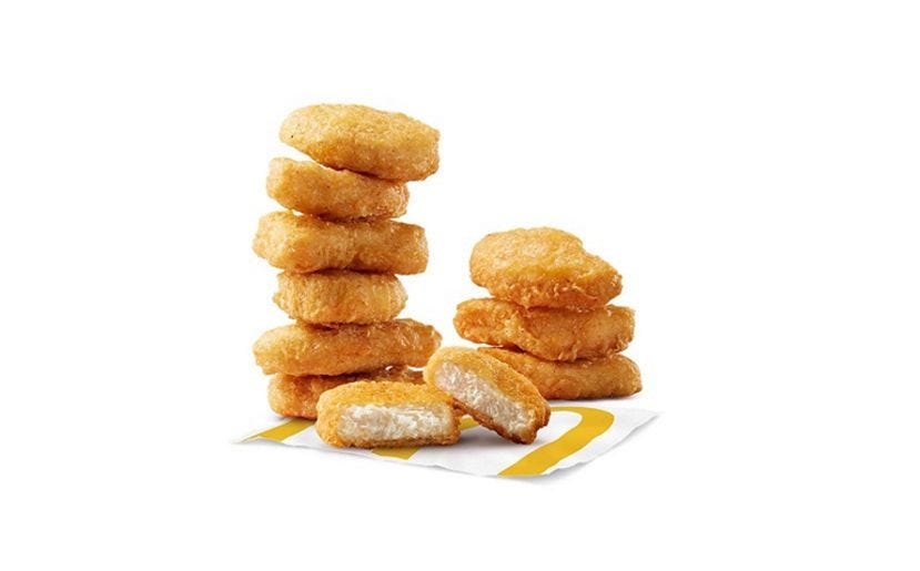 fried chicken nuggets arranged in stacks with one nugget cut in half resting on a branded paper