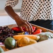 woman picking up vegetables in meal delivery box