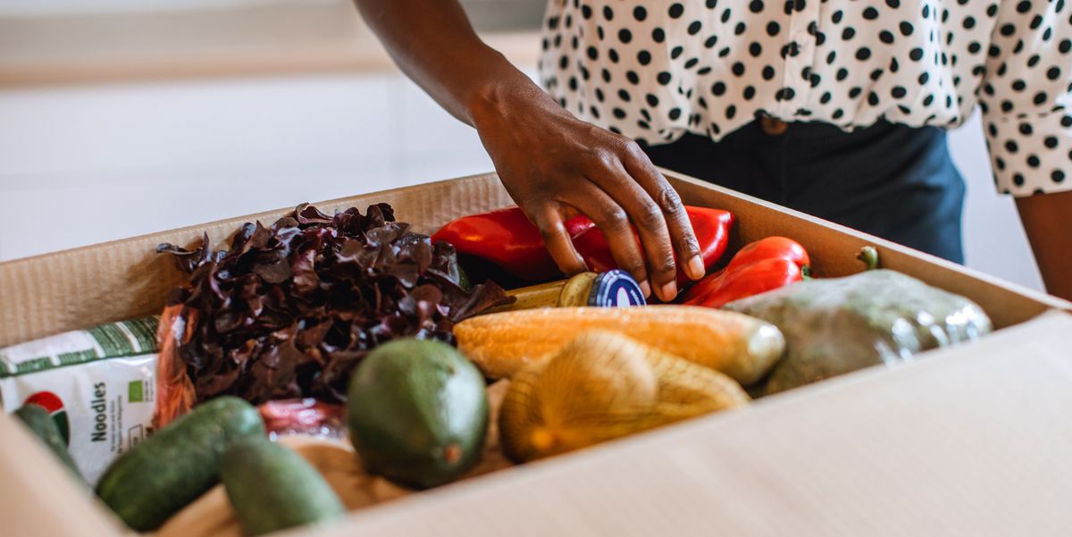 woman picking up vegetables in meal delivery box