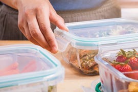 meal prepping by sorting berries, notes, and fresh food into clear glass containers