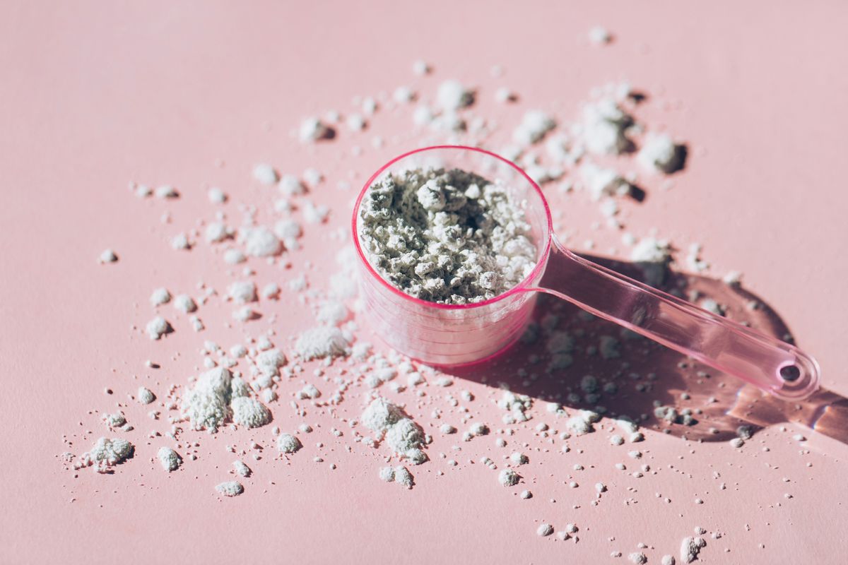 measuring spoon with collagen powder or alginate mask on pink background