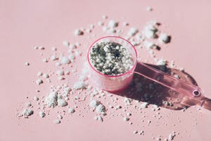 measuring spoon with collagen powder or alginate mask on pink background