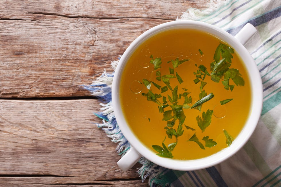 meat broth with parsley in bowl closeup horizontal top view