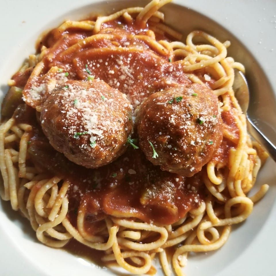 bowl of spaghetti and meatballs with sprinkles of cheese and italian seasoning on it