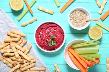 bowl of beetroot hummus, sesame, carrot and celery crudites and breadsticks