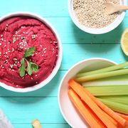 bowl of beetroot hummus, sesame, carrot and celery crudites and breadsticks