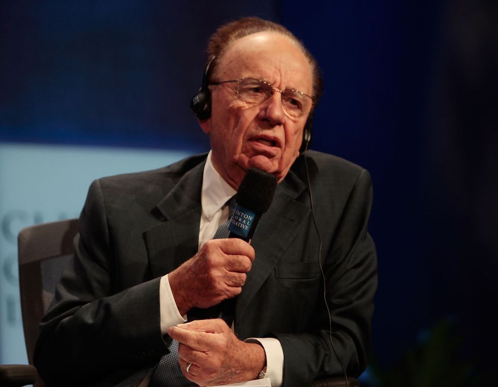 rupert murdoch wearing headphones and speaking into a microphone while sitting in a chair