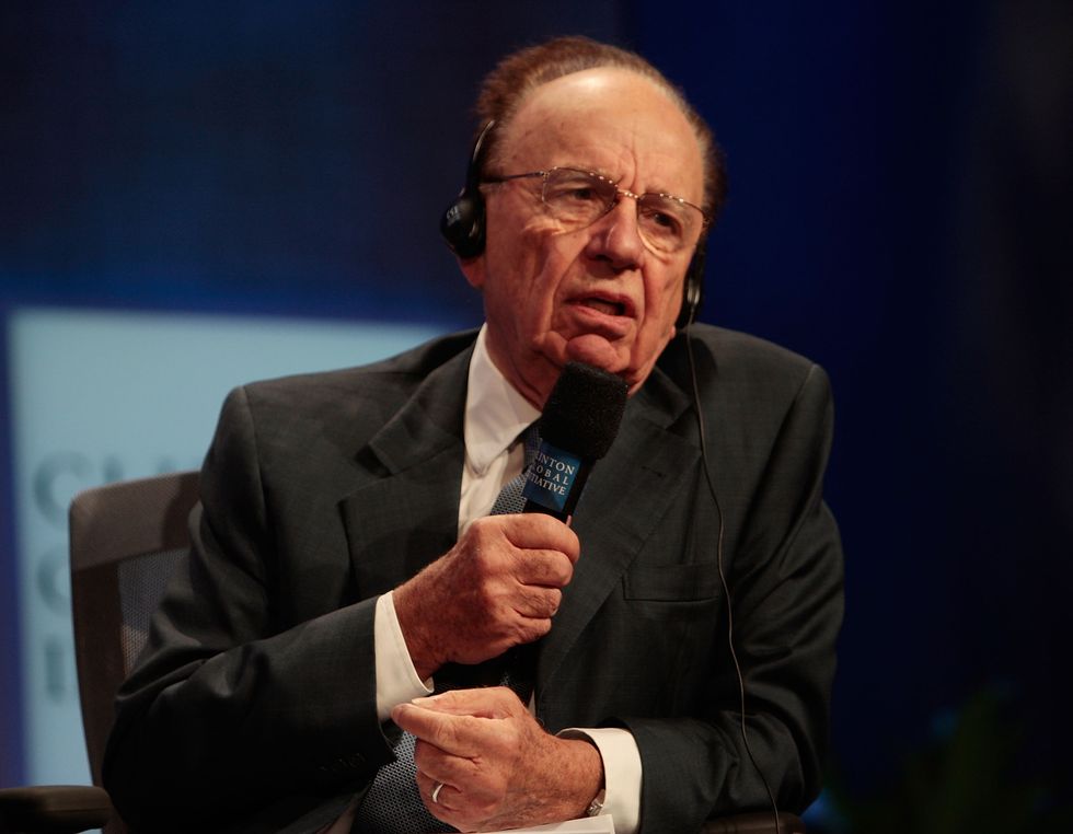rupert murdoch wearing headphones and speaking into a microphone while sitting in a chair