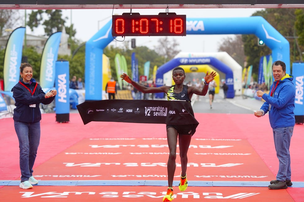 runner crossing finish line at a marathon with time displayed