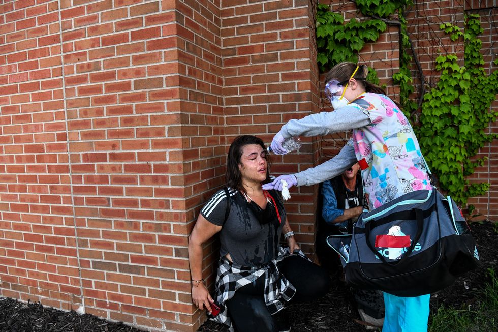 a medic protestor pours water on a woman's face during a demonstration to call for justice for george floyd in washington, dc