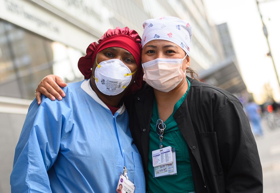 medical workers pose outside nyu langone health hospital as people applaud to show their gratitude to medical staff and essential workers on the front lines of the coronavirus pandemic on april 28, 2020 in new york city