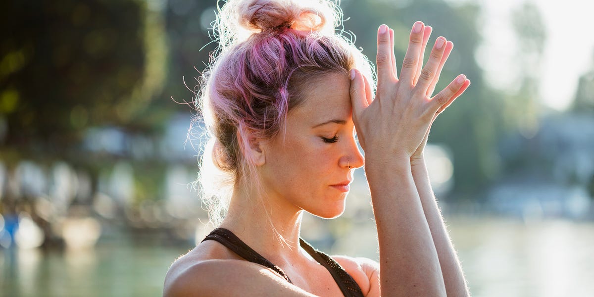 woman with pink hair and wearing workout clothes doing meditation outside woman with pink hair and wearing workout clothes doing meditation outside