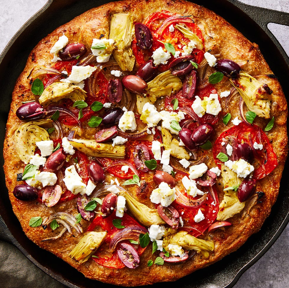 skillet pizza topped with olives, artichokes, tomatoes, feta, and onions