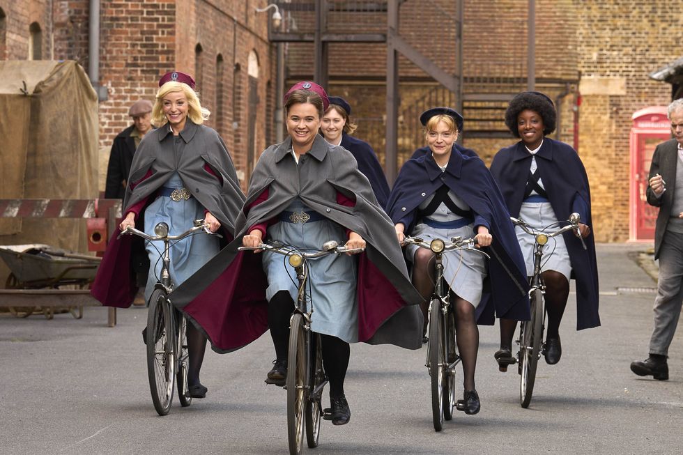 megan cusak, natalie quarry, helen george, and renee bailey in character riding their bikes on the set of call the midwife, season 13