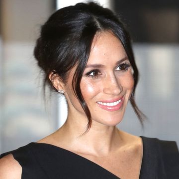 meghan markle smiles at an event with a glam updo hair style
