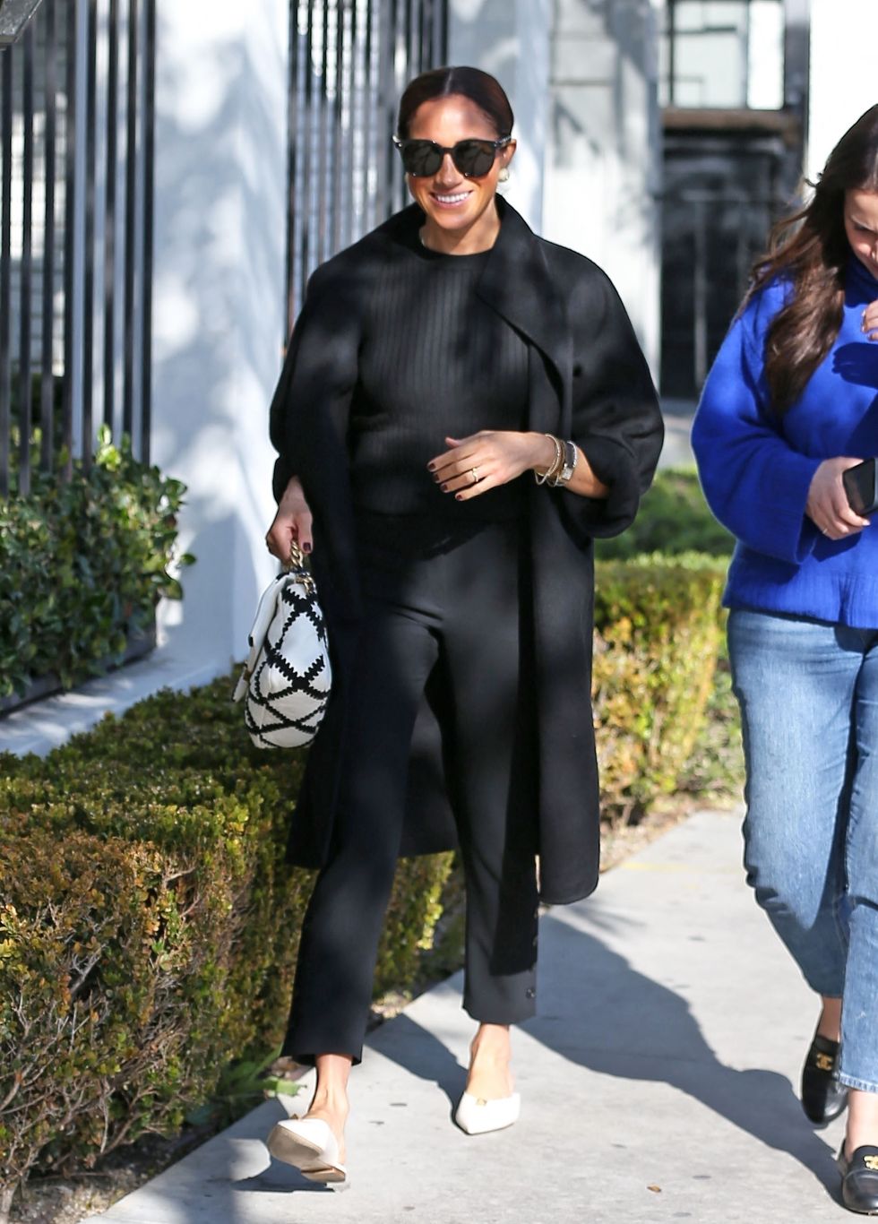 meghan markle walking while wearing an all black outfit and white flats