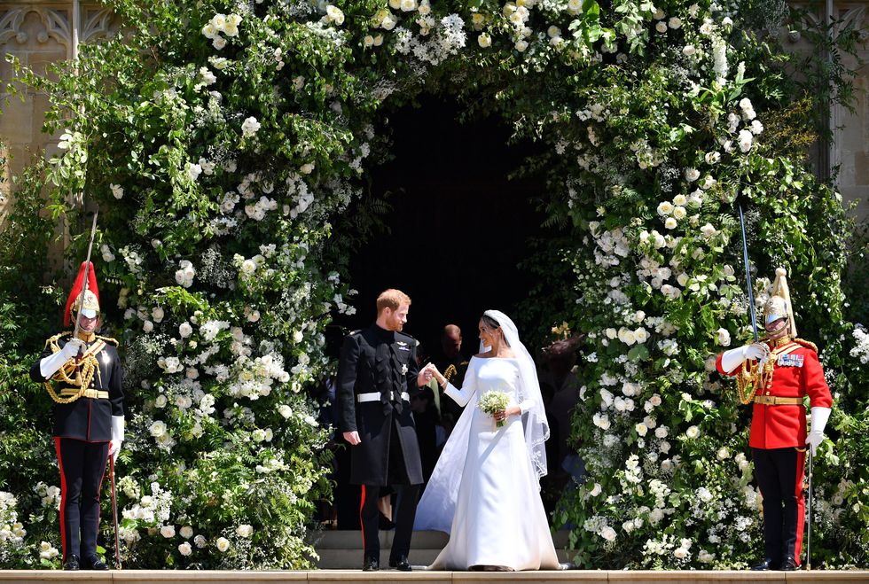 Meghan Markle and Prince Harry hold hands at the floral wall during the royal wedding.