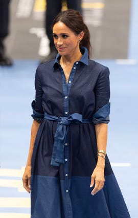 la duquesa de sussex con un vestido camisero denim y el pelo recogido en una coleta