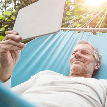 mejor tablet 2025 un hombre tumbado en una hamaca sujeta un ipad sin el logo de la manzana característico de la marca