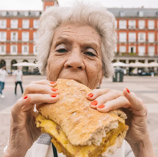 abuela comiendo bocadillo de tortilla en la plaza mayor de madrid