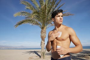 un hombre se aplica crema after sun en el pecho después de correr en la playa