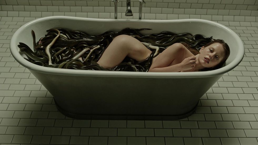 una chica en una bañera llena de serpientes en la cura del bienestar