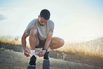 un hombre ata los cordones de sus zapatilla de running