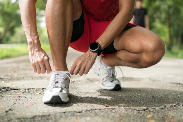 un corredor ata los cordones de sus zapatillas de running