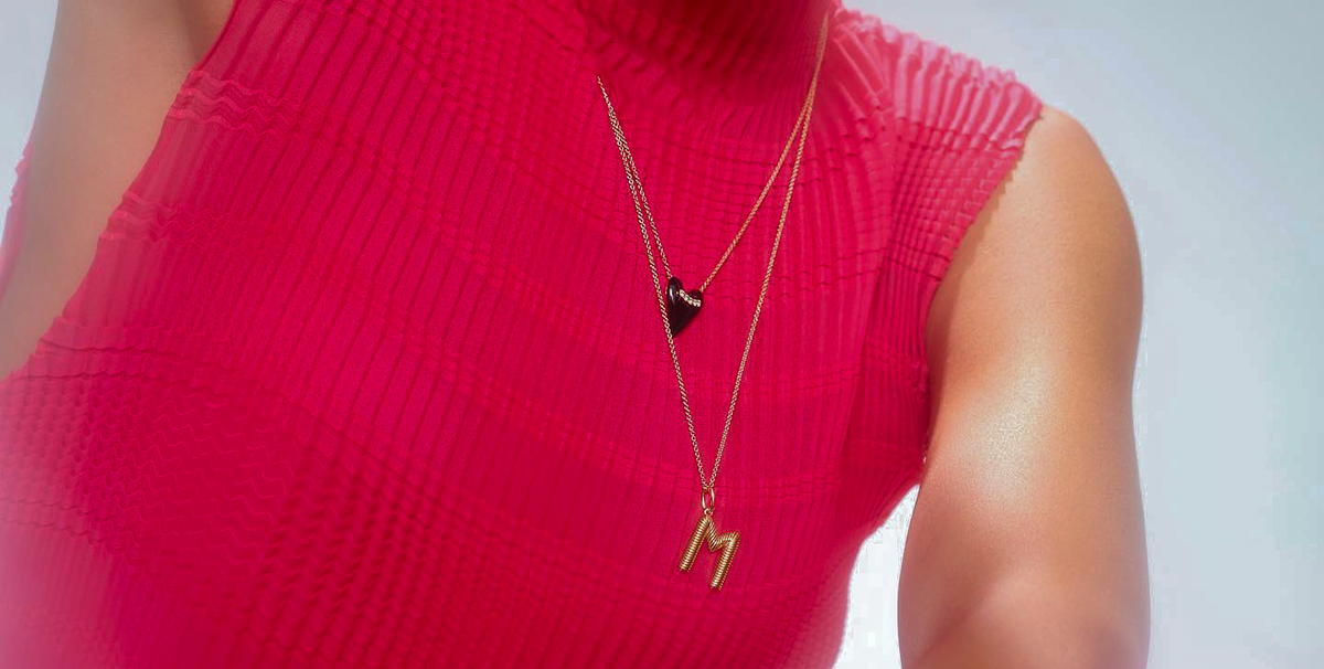 a model wears a pink mock neck sweater with two dainty necklaces