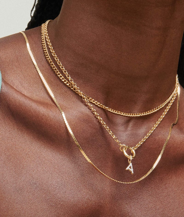 layered gold necklaces featuring a sparkling letter pendant