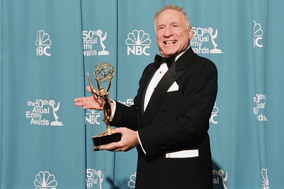 mel brooks is wearing a black tuxedo and posing for a photo while holding one of his emmy awards