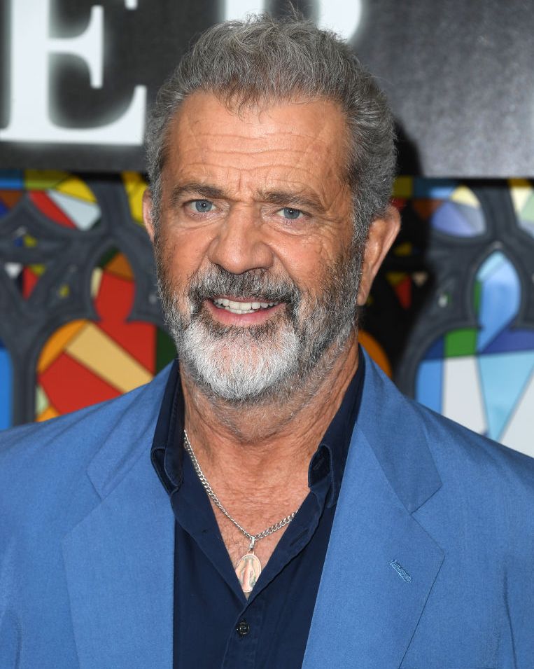 mel gibson smiling for a photograph while wearing a blue suit
