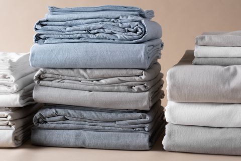 blue, gray and white bedding all bundled up in piles on top of each other