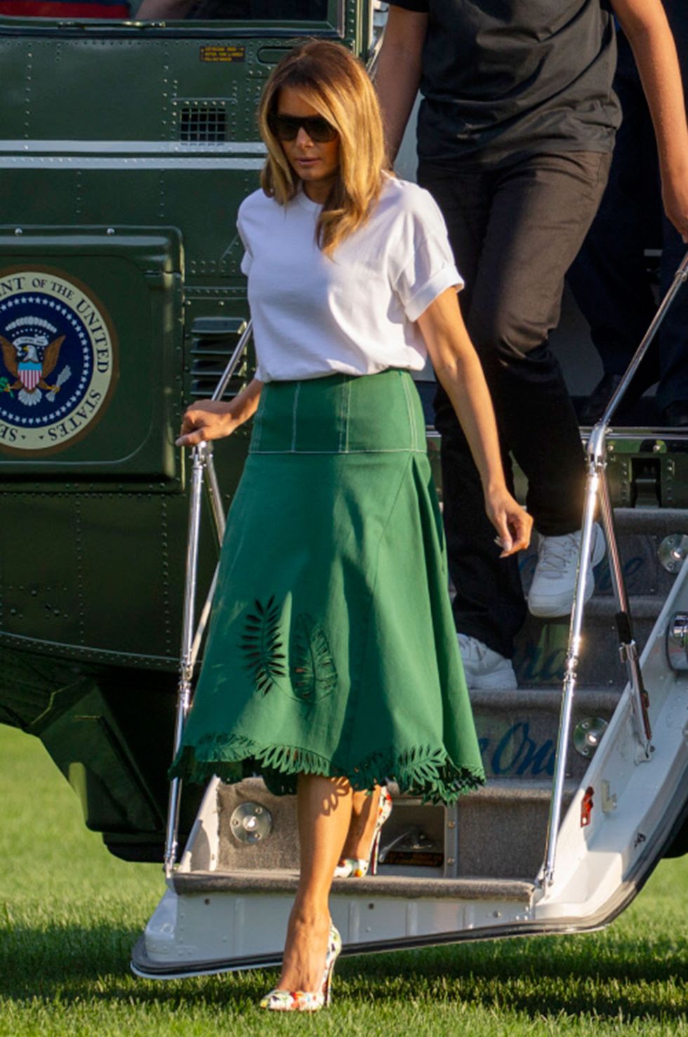 Melania Trump con camiseta básica blanca, falda verde de Fendi y stilettos de Loboutin