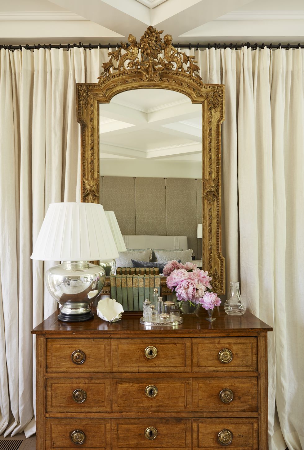 cream linen panels form a soft backdrop for a gilded mirror in the bedroom