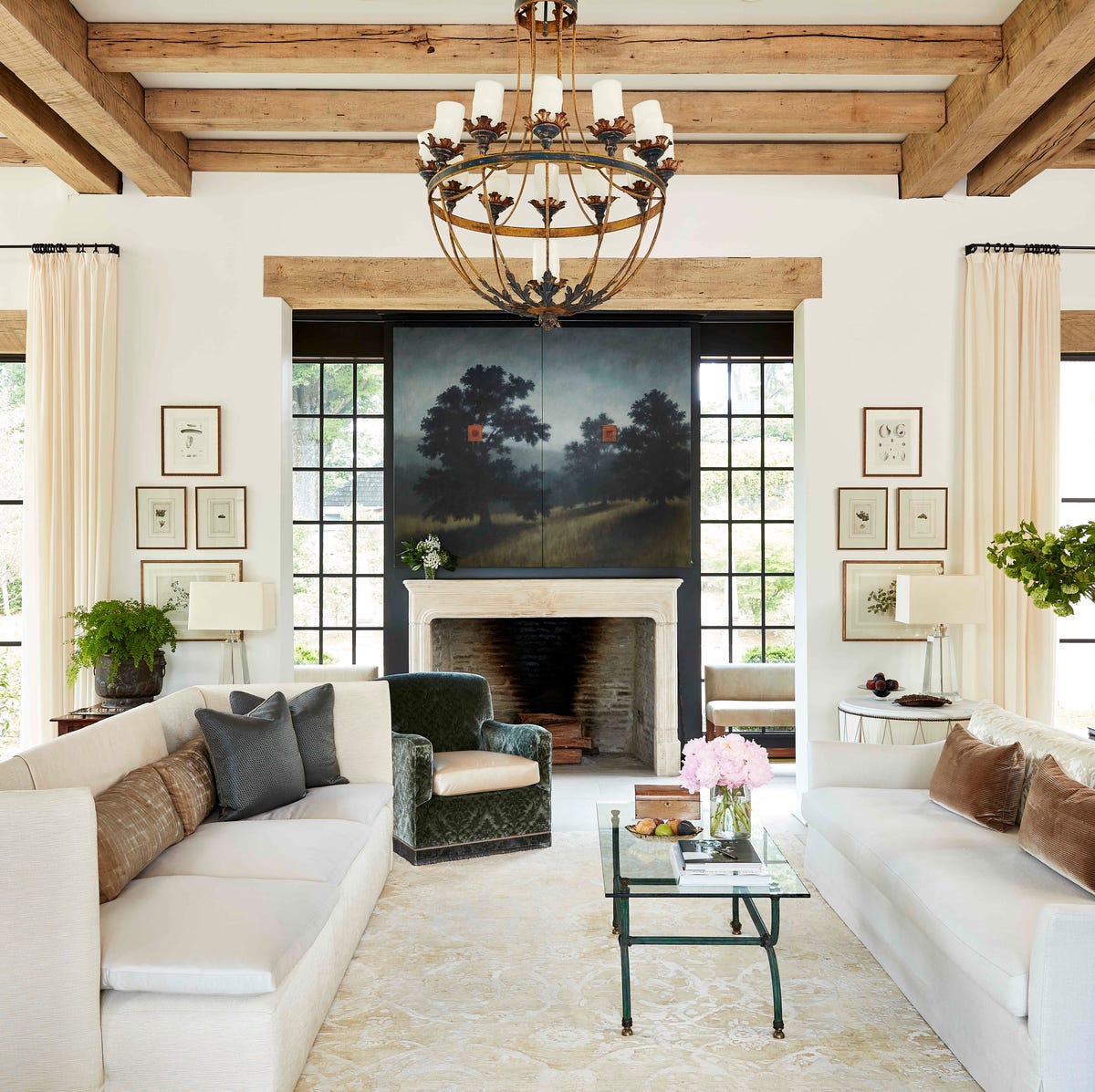 two sofas face each other in a large living space with a landscape painting hanging above the fireplace